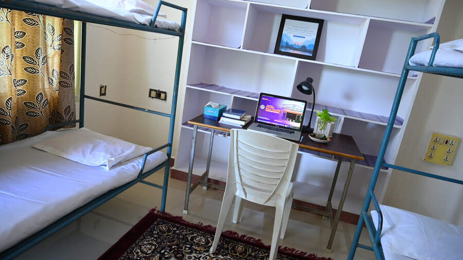 A residence hall room with bunk beds and a study desk