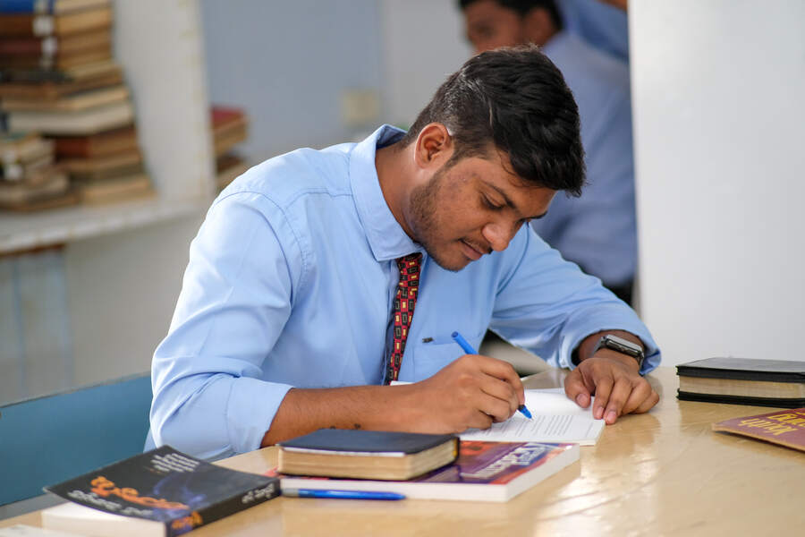 A student writing notes at a library desk